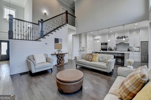 living room with a towering ceiling, crown molding, and dark wood-type flooring