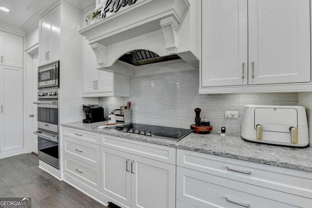 kitchen featuring stainless steel appliances, light stone counters, decorative backsplash, white cabinets, and custom exhaust hood