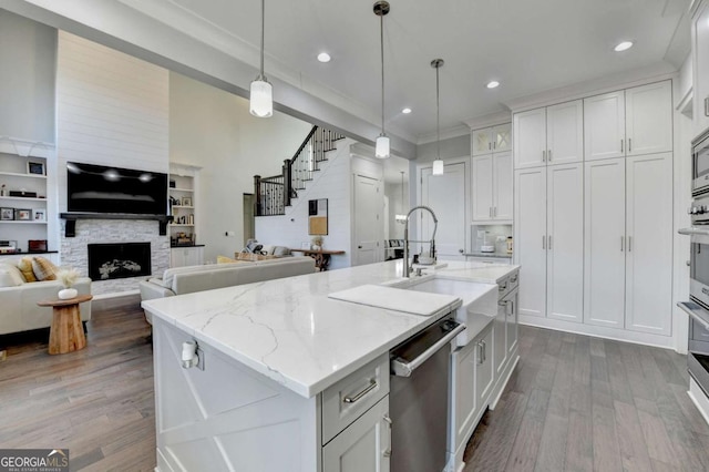 kitchen with white cabinets, appliances with stainless steel finishes, a fireplace, and hanging light fixtures