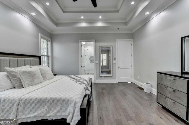 bedroom with a raised ceiling, connected bathroom, ceiling fan, and hardwood / wood-style flooring