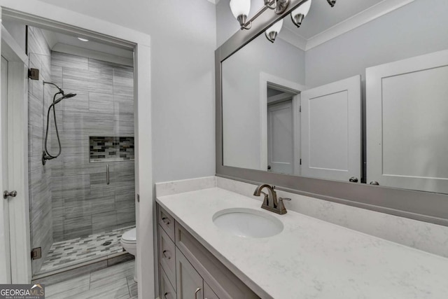 bathroom with crown molding, a shower with door, vanity, and toilet