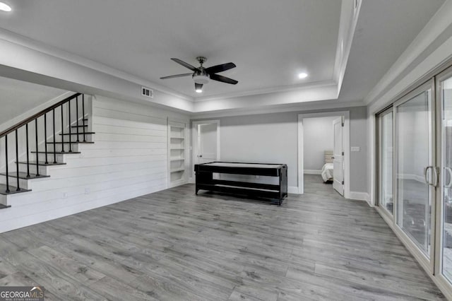 unfurnished bedroom with light wood-type flooring, a tray ceiling, ceiling fan, and ornamental molding