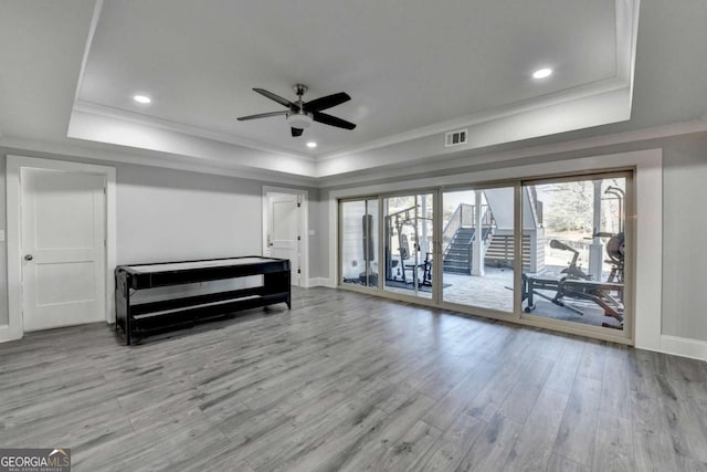 unfurnished bedroom featuring access to outside, light hardwood / wood-style floors, a raised ceiling, and ceiling fan