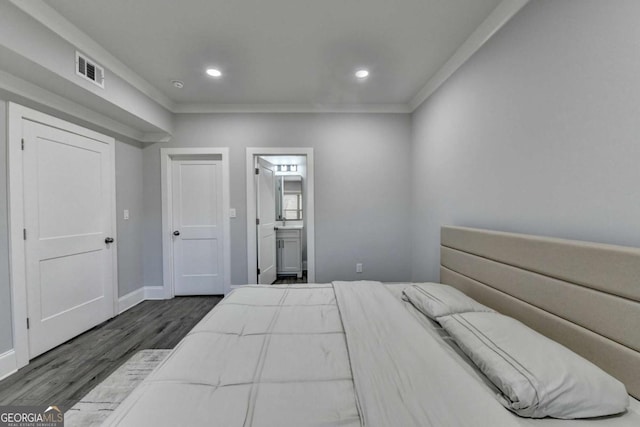 bedroom featuring connected bathroom, crown molding, and dark hardwood / wood-style flooring