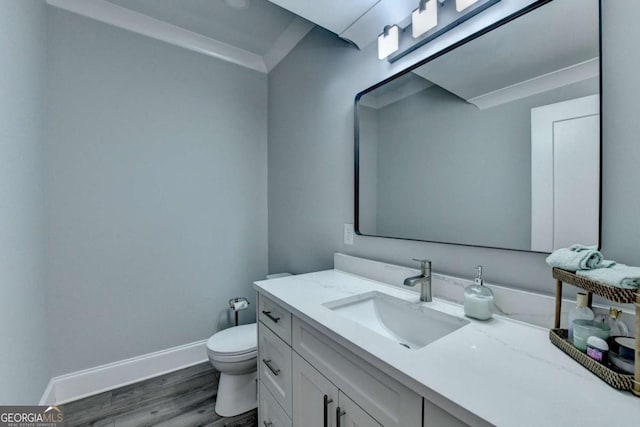 bathroom featuring crown molding, hardwood / wood-style floors, vanity, and toilet