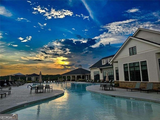 pool at dusk featuring a patio