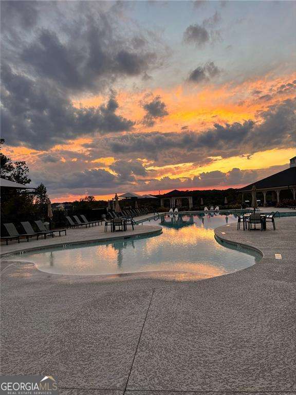 pool at dusk featuring a patio