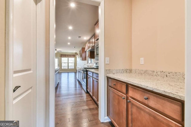 kitchen with ceiling fan, dark hardwood / wood-style flooring, light stone countertops, and gas range