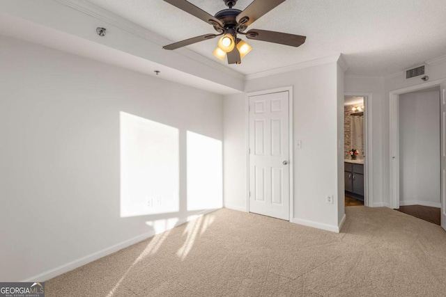 unfurnished bedroom with connected bathroom, carpet flooring, ceiling fan, crown molding, and a closet