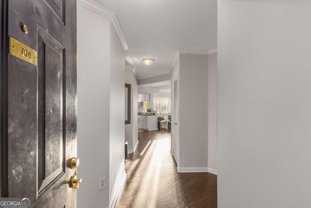 hallway featuring dark hardwood / wood-style flooring, a textured ceiling, and ornamental molding