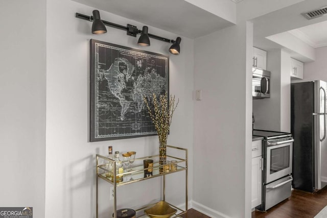 room details with crown molding, stainless steel appliances, and dark hardwood / wood-style floors