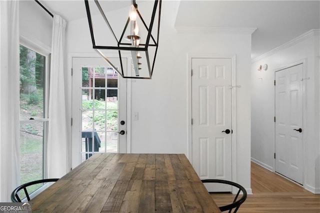 dining space featuring crown molding, hardwood / wood-style floors, a healthy amount of sunlight, and a notable chandelier