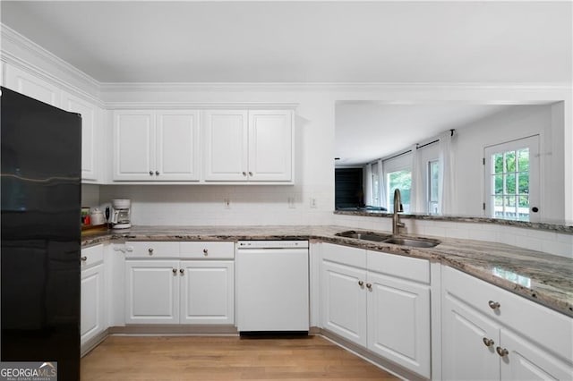 kitchen with black fridge, white cabinetry, sink, and white dishwasher