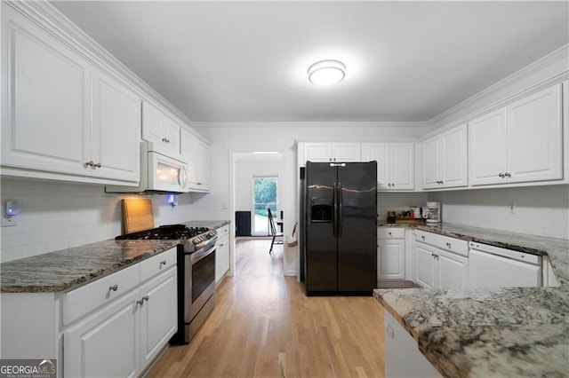 kitchen with white cabinetry, light hardwood / wood-style flooring, dark stone countertops, white appliances, and decorative backsplash