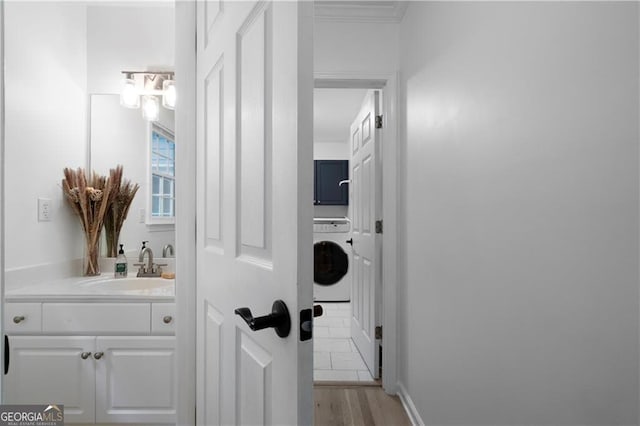 bathroom with washer / clothes dryer, crown molding, hardwood / wood-style floors, and vanity