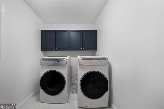 laundry area featuring washer and clothes dryer, light tile patterned floors, and cabinets