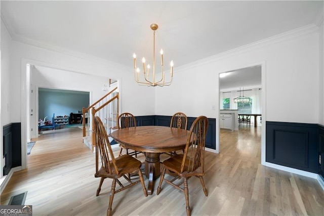 dining space with light hardwood / wood-style floors, crown molding, and a notable chandelier