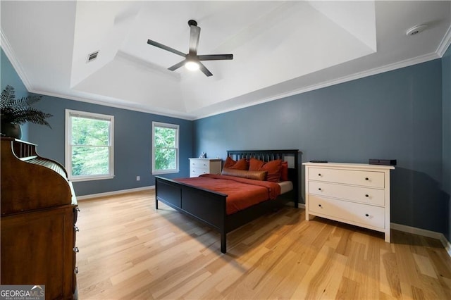 bedroom with a raised ceiling, ceiling fan, crown molding, and light wood-type flooring