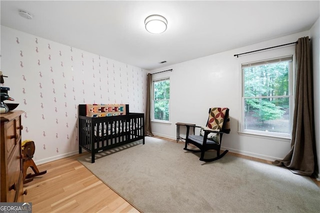 bedroom featuring light hardwood / wood-style floors and a crib