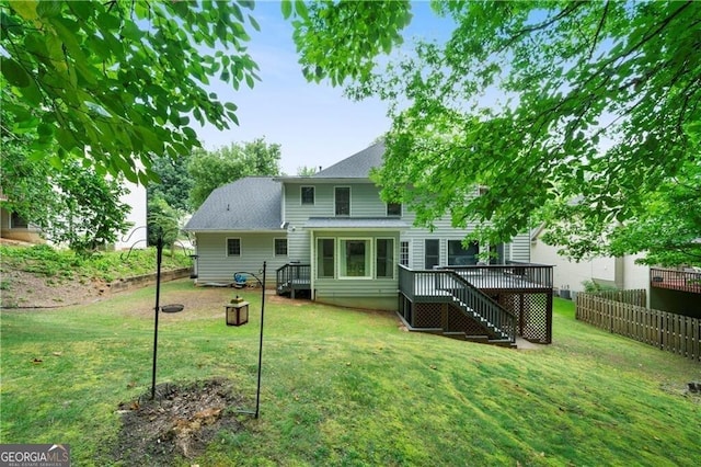 rear view of property featuring a lawn and a wooden deck