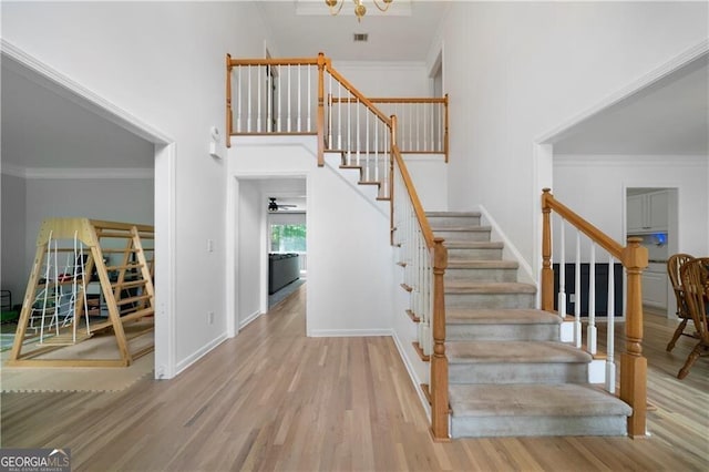 stairs featuring hardwood / wood-style flooring, ceiling fan, and ornamental molding