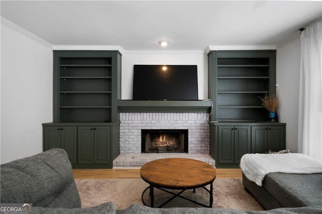 living room featuring light hardwood / wood-style floors, ornamental molding, built in features, and a brick fireplace