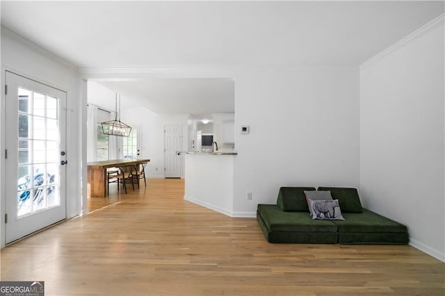 living area featuring light hardwood / wood-style floors, an inviting chandelier, and ornamental molding