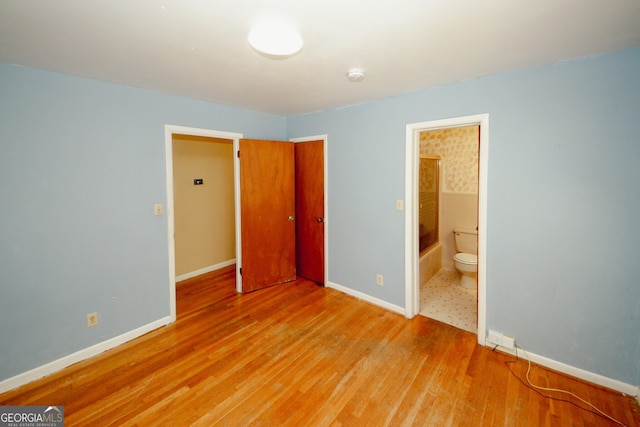 unfurnished bedroom with light wood-type flooring and connected bathroom