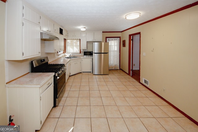 kitchen featuring appliances with stainless steel finishes, light tile patterned flooring, tile countertops, and white cabinetry