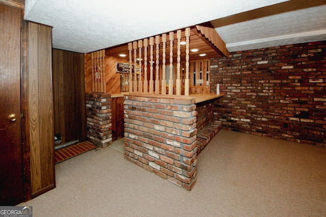 bar featuring brick wall, a textured ceiling, light carpet, and wooden walls