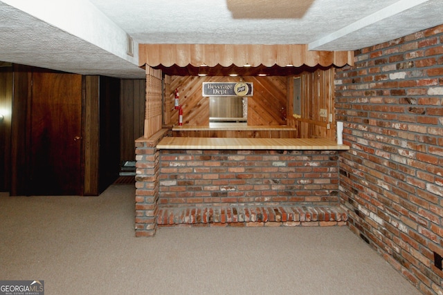 bar with carpet floors, a textured ceiling, brick wall, and wood walls