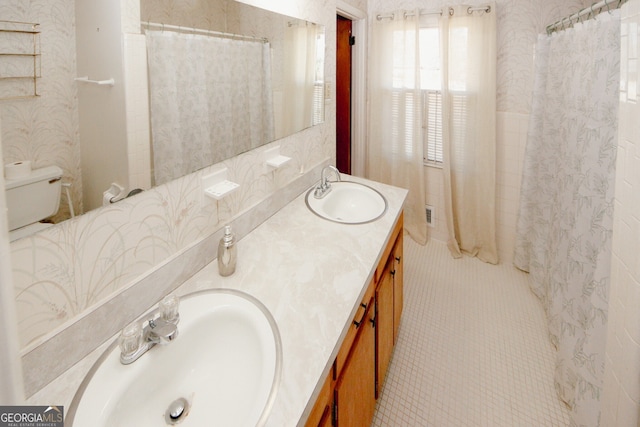 bathroom with toilet, vanity, and tile patterned flooring