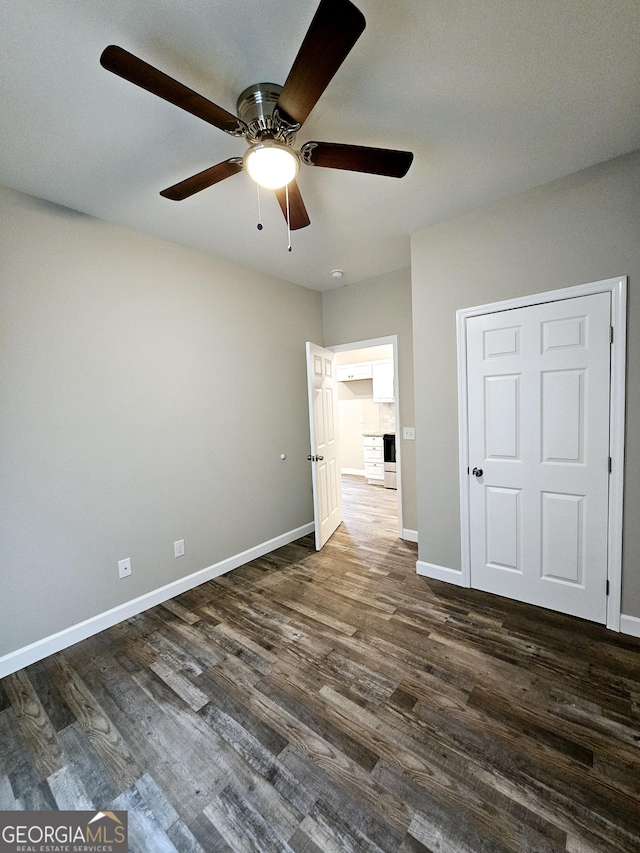 unfurnished bedroom with ceiling fan and dark wood-type flooring