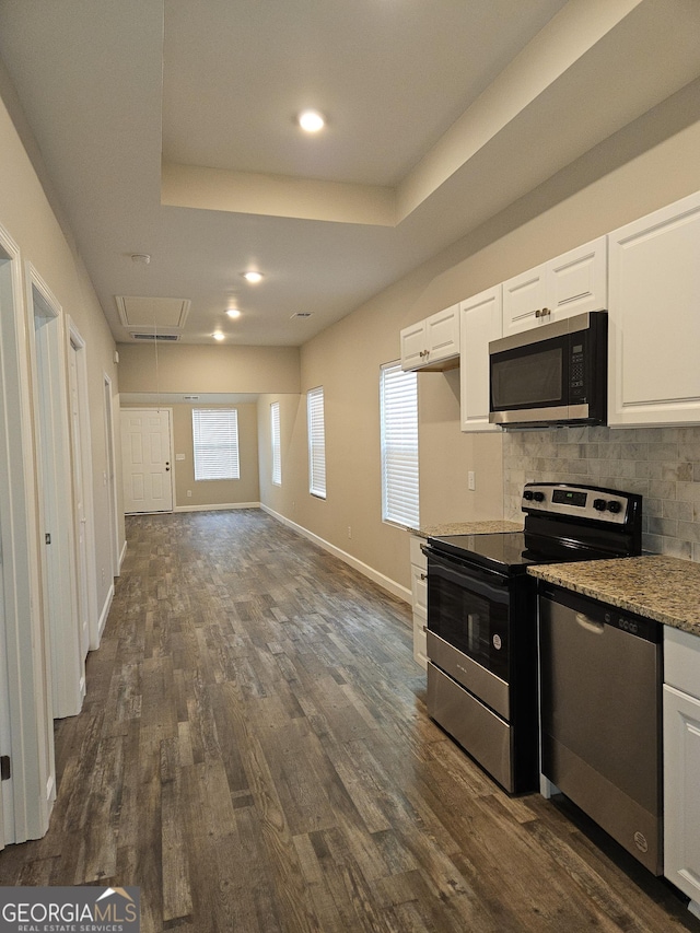 kitchen with backsplash, a tray ceiling, stainless steel appliances, white cabinets, and dark hardwood / wood-style flooring