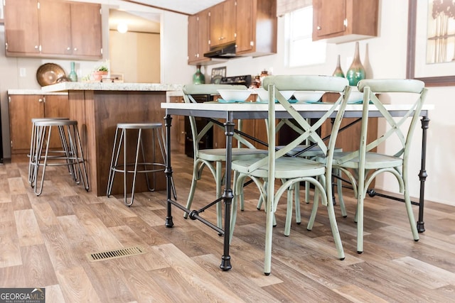 kitchen with a breakfast bar, light hardwood / wood-style floors, and kitchen peninsula