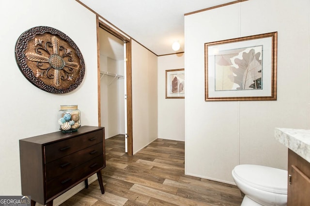 bathroom with vanity, wood-type flooring, ornamental molding, and toilet