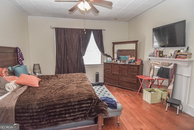 bedroom with light wood-type flooring, ceiling fan, and crown molding