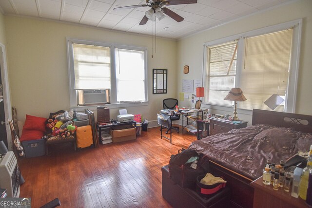 bedroom with dark hardwood / wood-style floors, crown molding, ceiling fan, and cooling unit