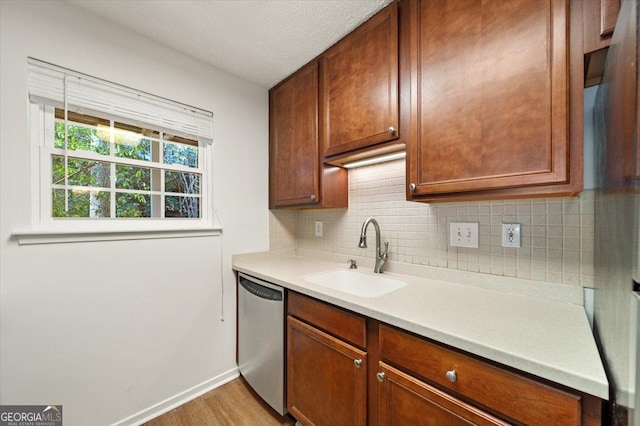 kitchen featuring tasteful backsplash, sink, stainless steel dishwasher, and light hardwood / wood-style floors