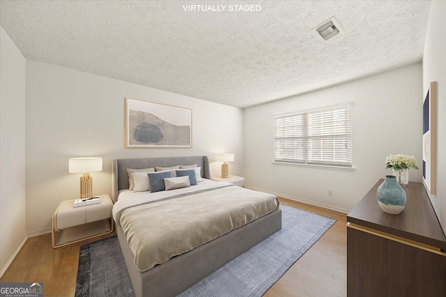 bedroom featuring a textured ceiling and light hardwood / wood-style flooring