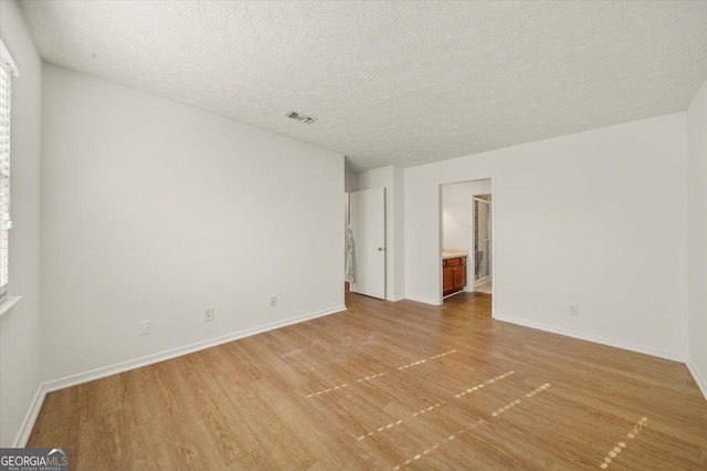 spare room featuring light wood-type flooring and a textured ceiling