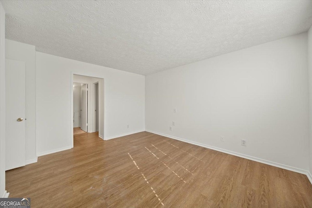 unfurnished room with wood-type flooring and a textured ceiling