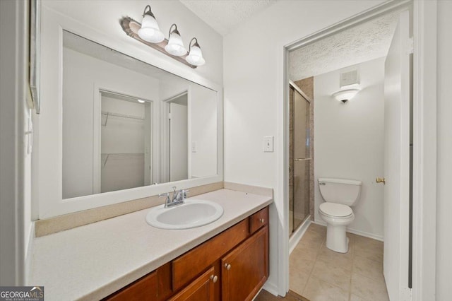 bathroom featuring tile patterned floors, vanity, a textured ceiling, toilet, and a shower with shower door