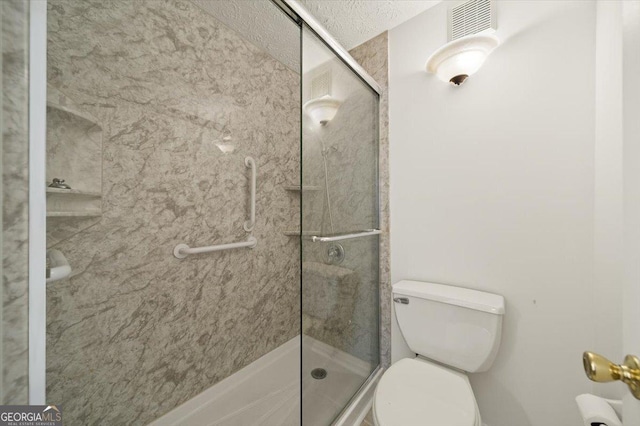 bathroom with a shower with shower door, a textured ceiling, and toilet