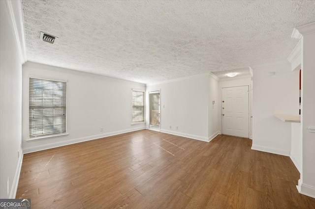 spare room with hardwood / wood-style floors, plenty of natural light, and crown molding