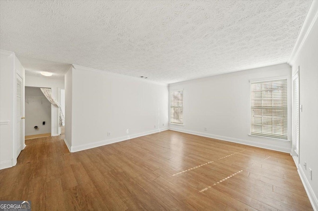 unfurnished room featuring a textured ceiling, wood-type flooring, and crown molding