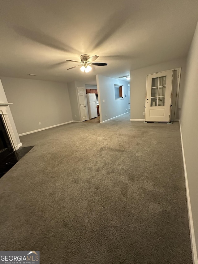 unfurnished living room with dark colored carpet and ceiling fan