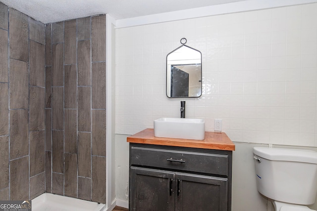 bathroom featuring walk in shower, vanity, tile walls, and toilet