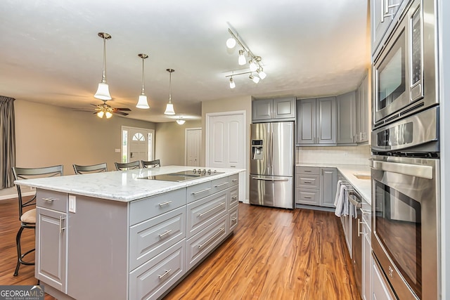 kitchen with gray cabinetry, a breakfast bar, a kitchen island, and appliances with stainless steel finishes