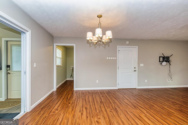 unfurnished room with hardwood / wood-style flooring and a notable chandelier